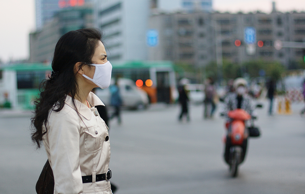 Beautiful Chinese woman wearing a white face mask against pollution or disease